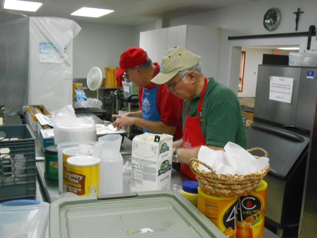 Two men working in a kitchen preparing food.
