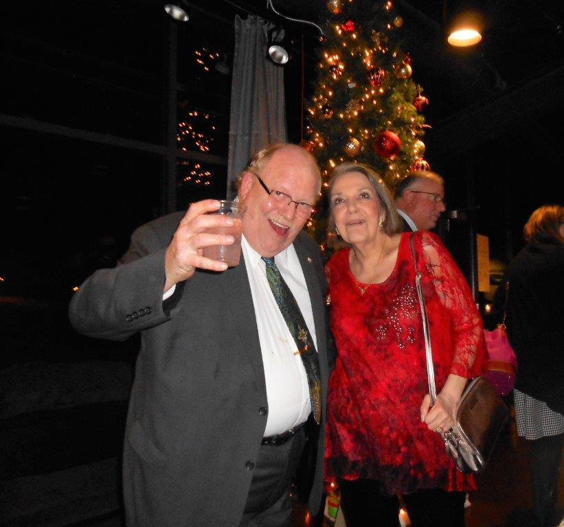 A man and woman posing for a picture in front of a christmas tree.