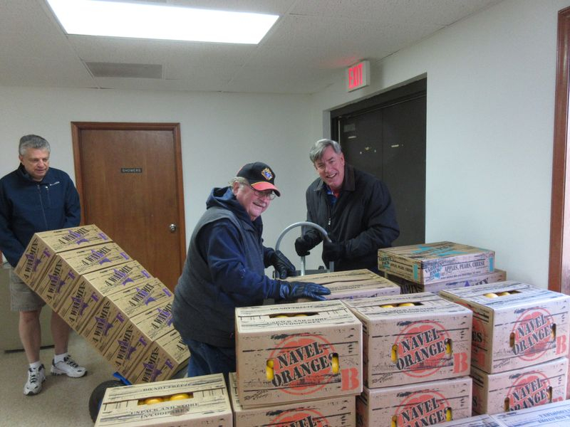 Two men standing next to boxes of beer.