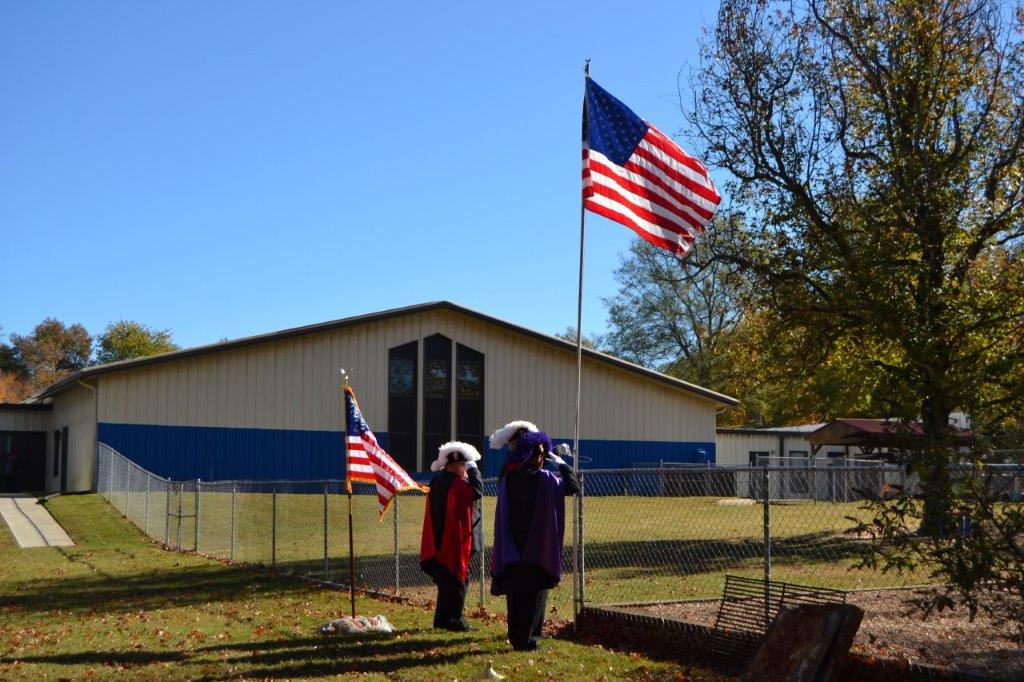 Two people standing next to a building with american flags.
