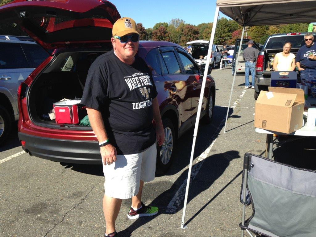 A man standing next to an open trunk of a car.