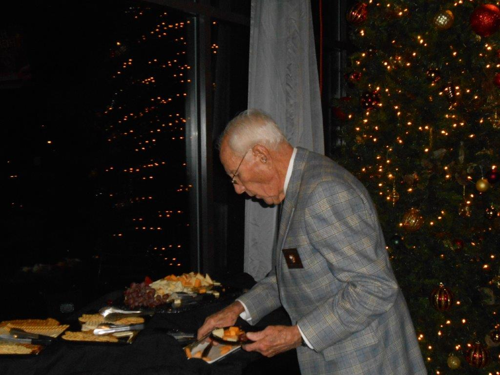 A man in a suit cutting food on top of a table.
