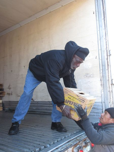 A man holding onto a box while another man lays on the ground.